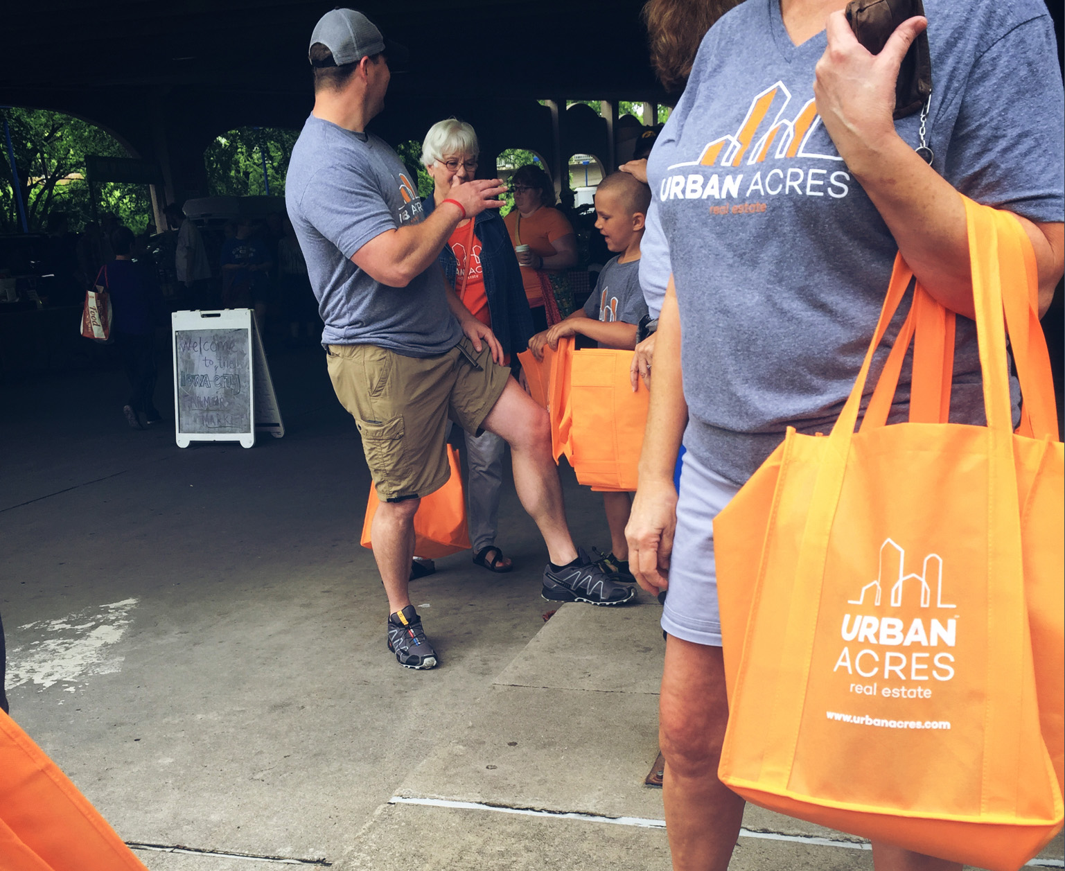 A group of individuals holding orange Urban Acres canvas bags
