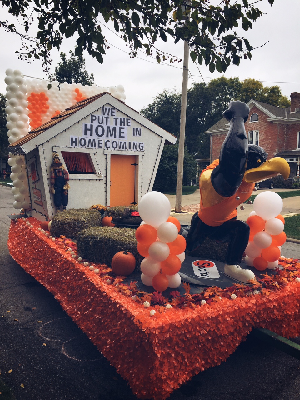 A parade float with a Herky mascot and a house reading "We put the home in homecoming"