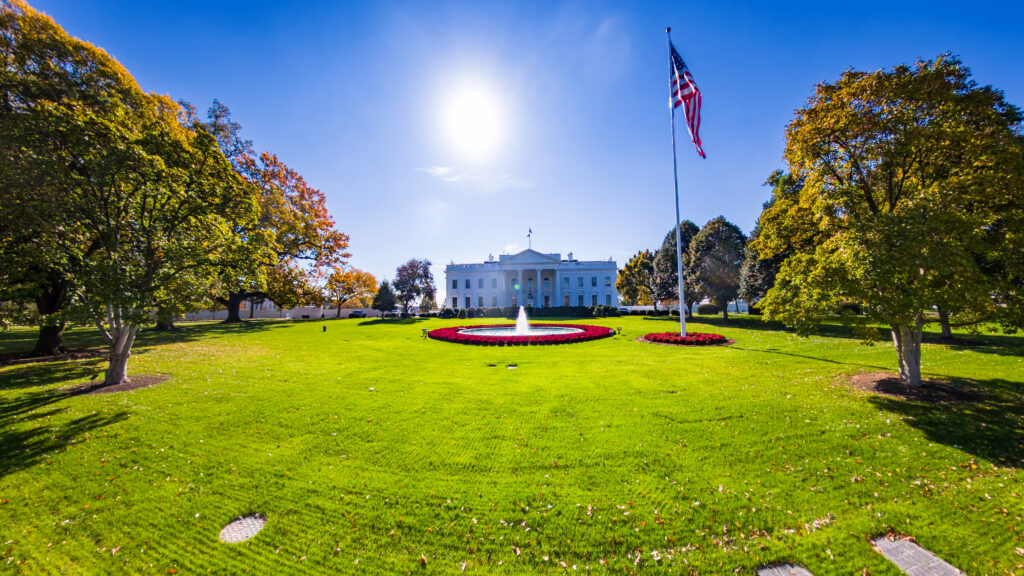 Iconic front view of the White House under sun and clear blue sky