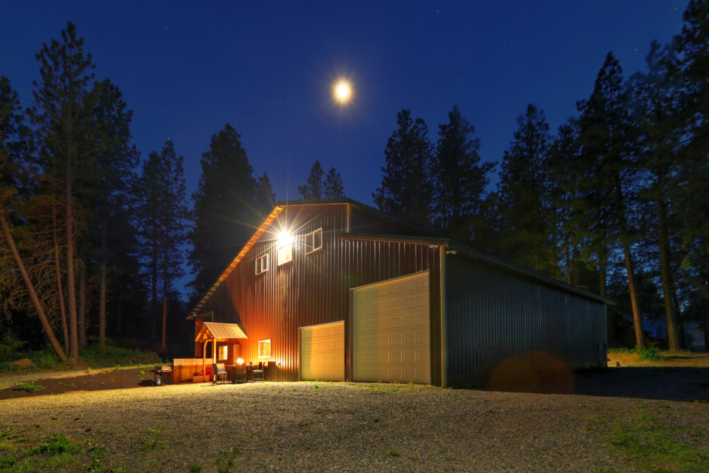 Barndominium at night with large garage and outdoor living area