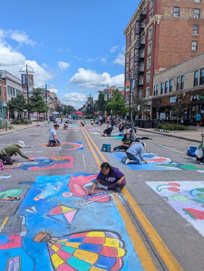 Woman drawing on a chalk mural at Rock the Chalk in downtown Iowa City