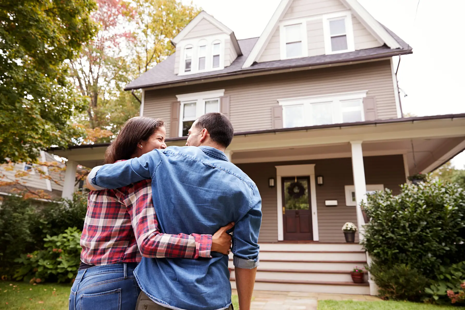 Happy couple embracing in front of their first home