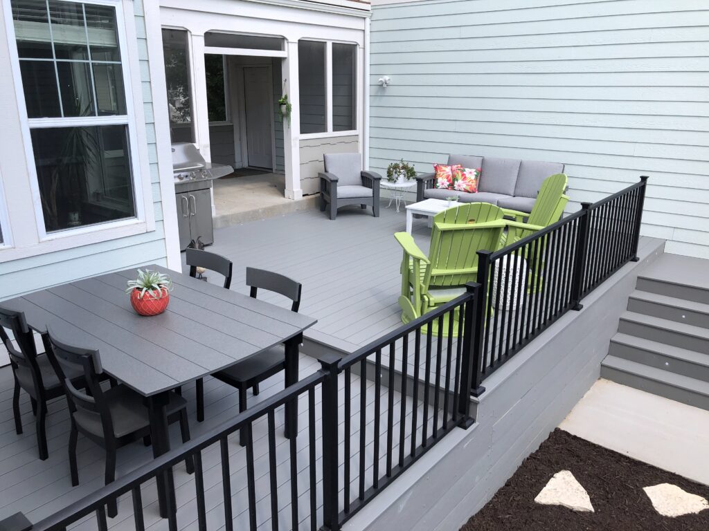 Gray composite deck with black railing and brightly colored patio furniture 