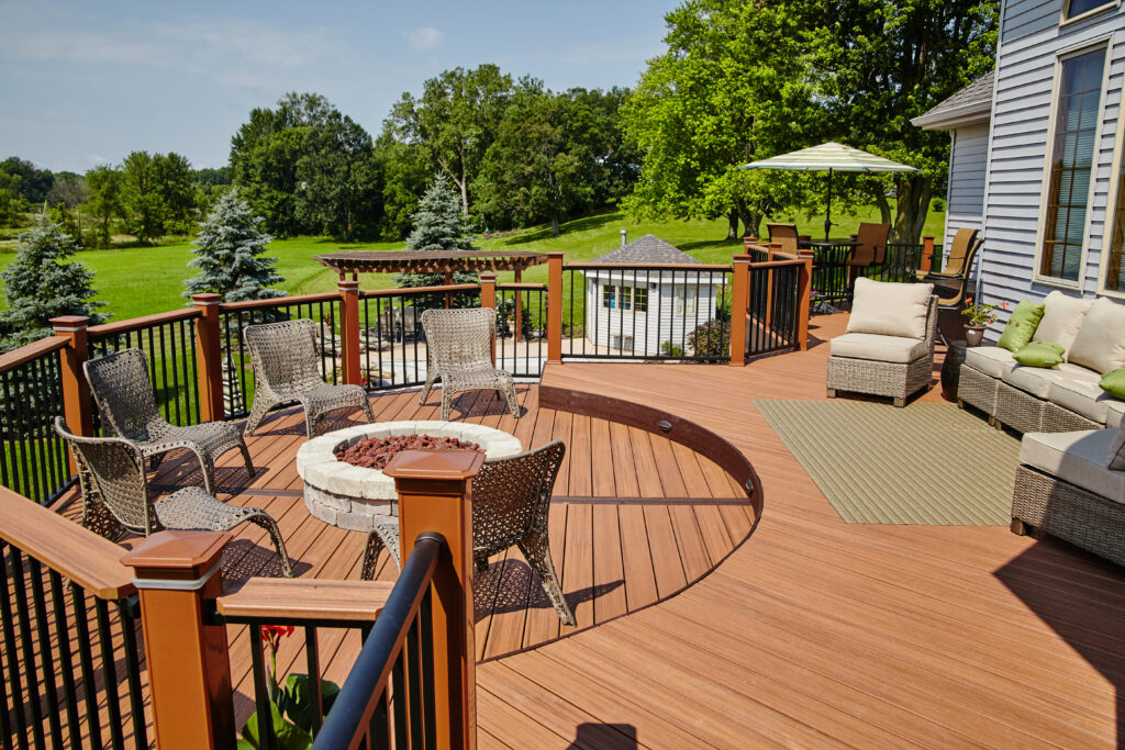Luxury outdoor deck with fire pit seating overlooking a green lawn