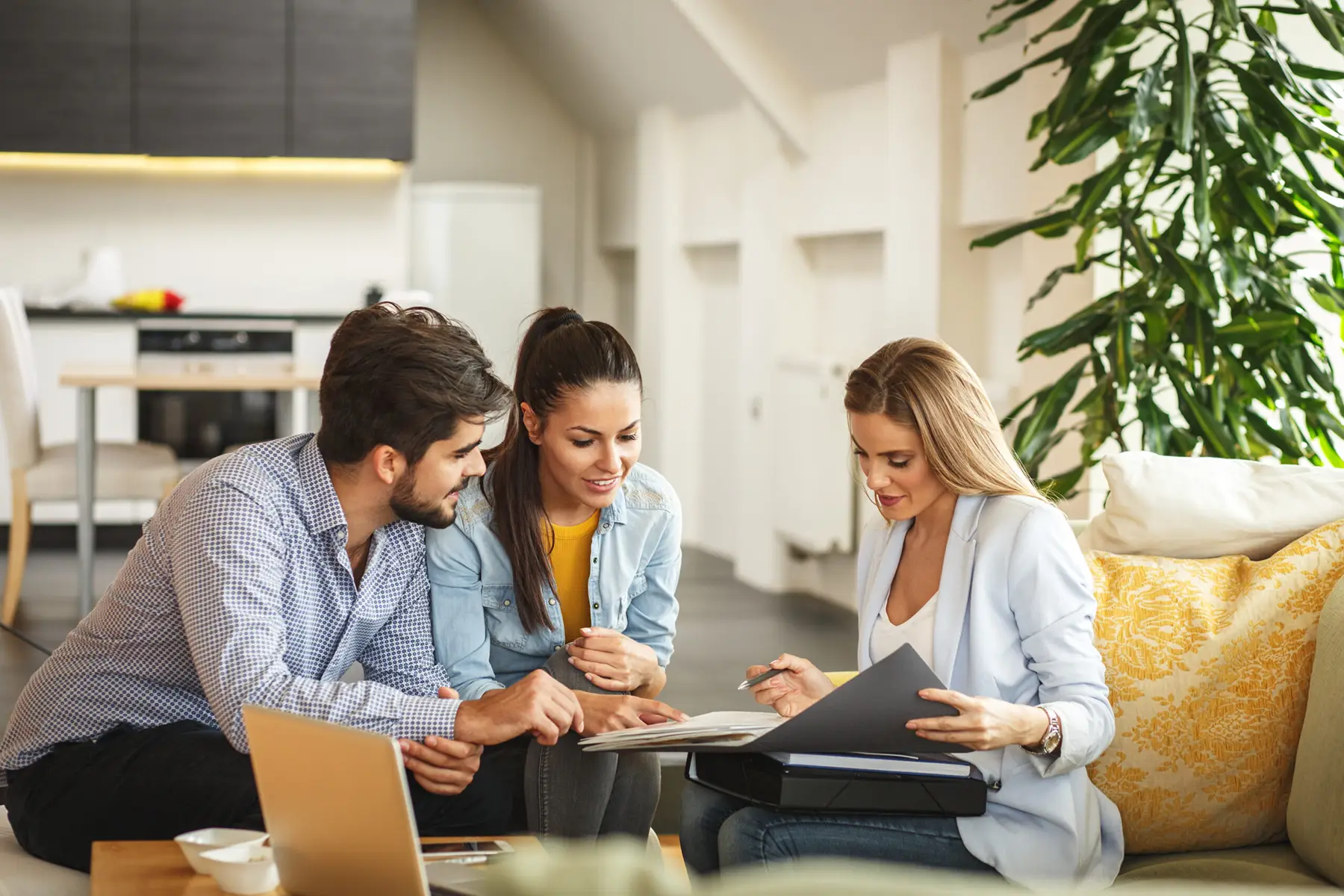 Female real estate agent reviews buyer's agreement with couple