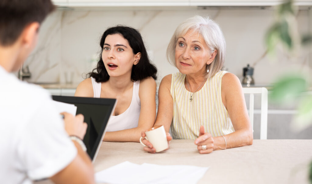 Older woman and her adult daughter meeting with a REALTOR to discuss a real estate sale