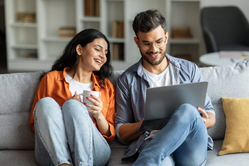 Young couple on a sofa with a laptop browsing the internet