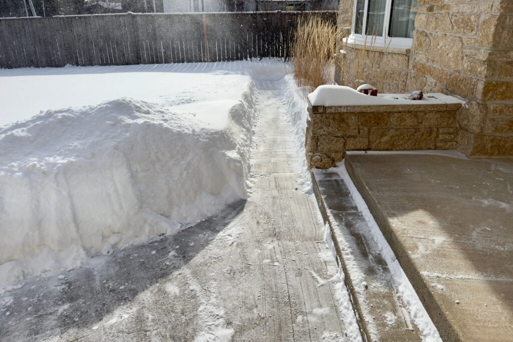A snow-covered yard and a cleared path around the house