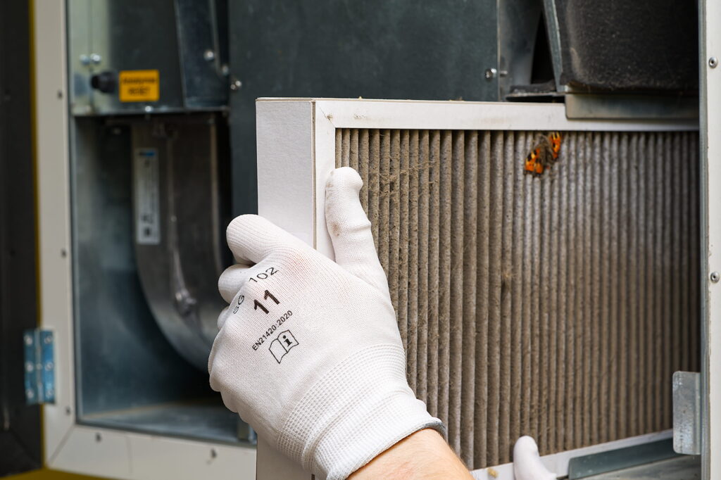 Technician changing a dirty HVAC filter in a home