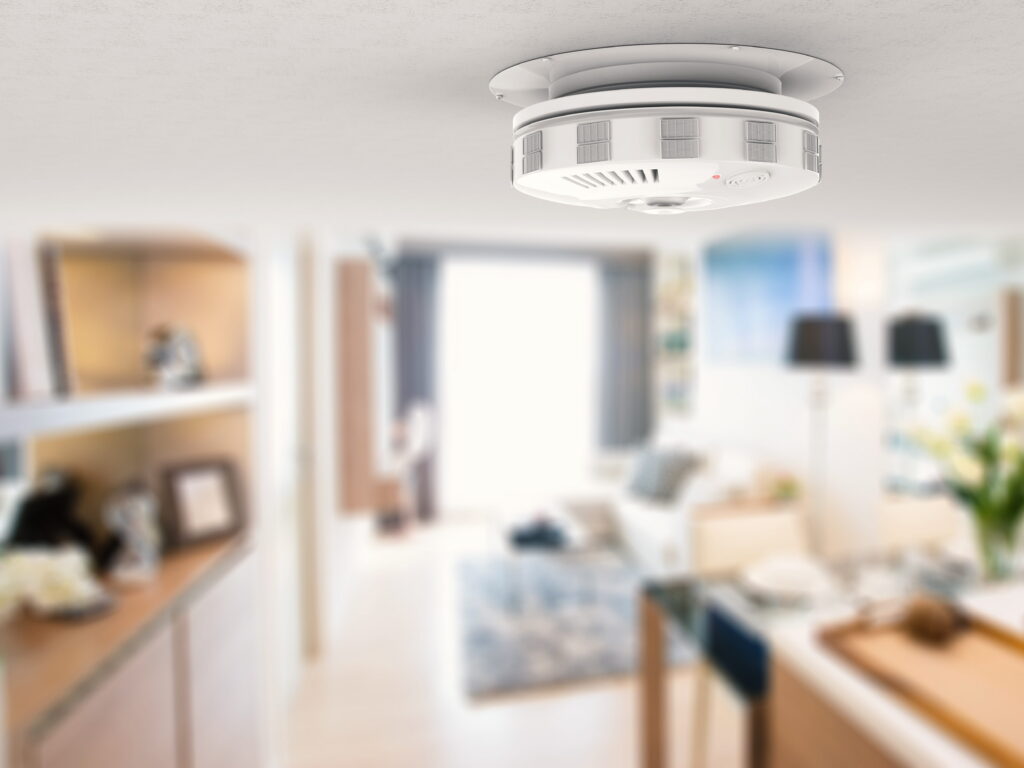 Smoke detector in a home with living area in the background