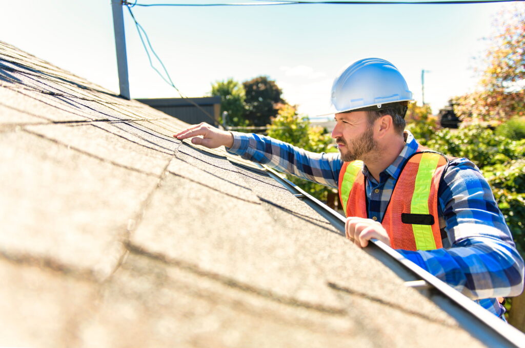 Man in a hard hat inspecting a roof