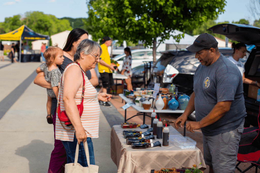People visiting a vendor booth at the Coralville Farmers Market in Coralville, Iowa