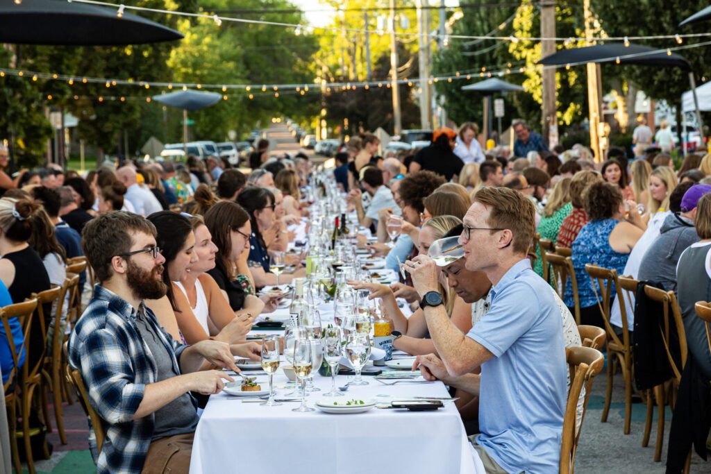 People sitting at tables and having conversation in downtown Iowa City during the Farm to Street dinner