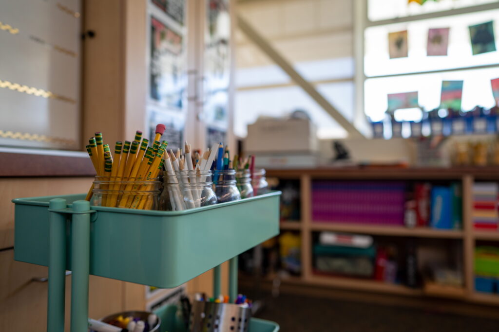 Teal cart filled with jars of colored pencils for an elementary school classroom