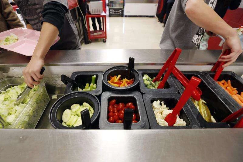 Elementary school students helping themselves at a salad bar during lunch