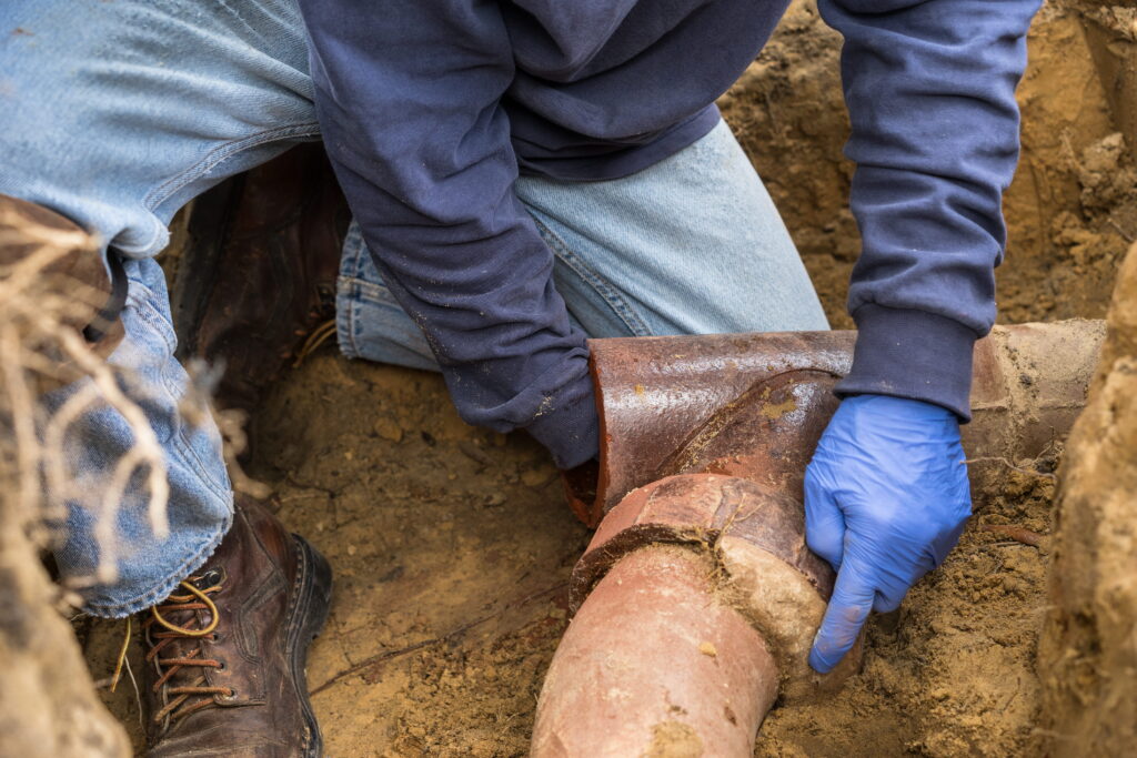 Closeup of a man digging out a clogged sewer line